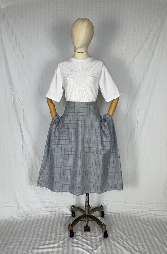 Mannequin wearing a white top and blue plaid checkered skirt against a plain background
