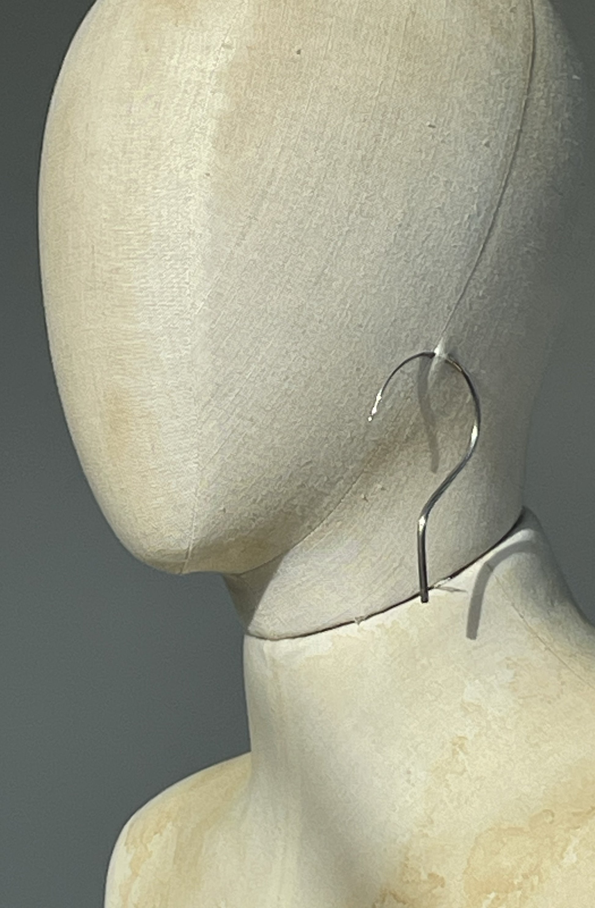 Silver hanger shaped unisex earring by Cunnington & Sanderson on a mannequin head