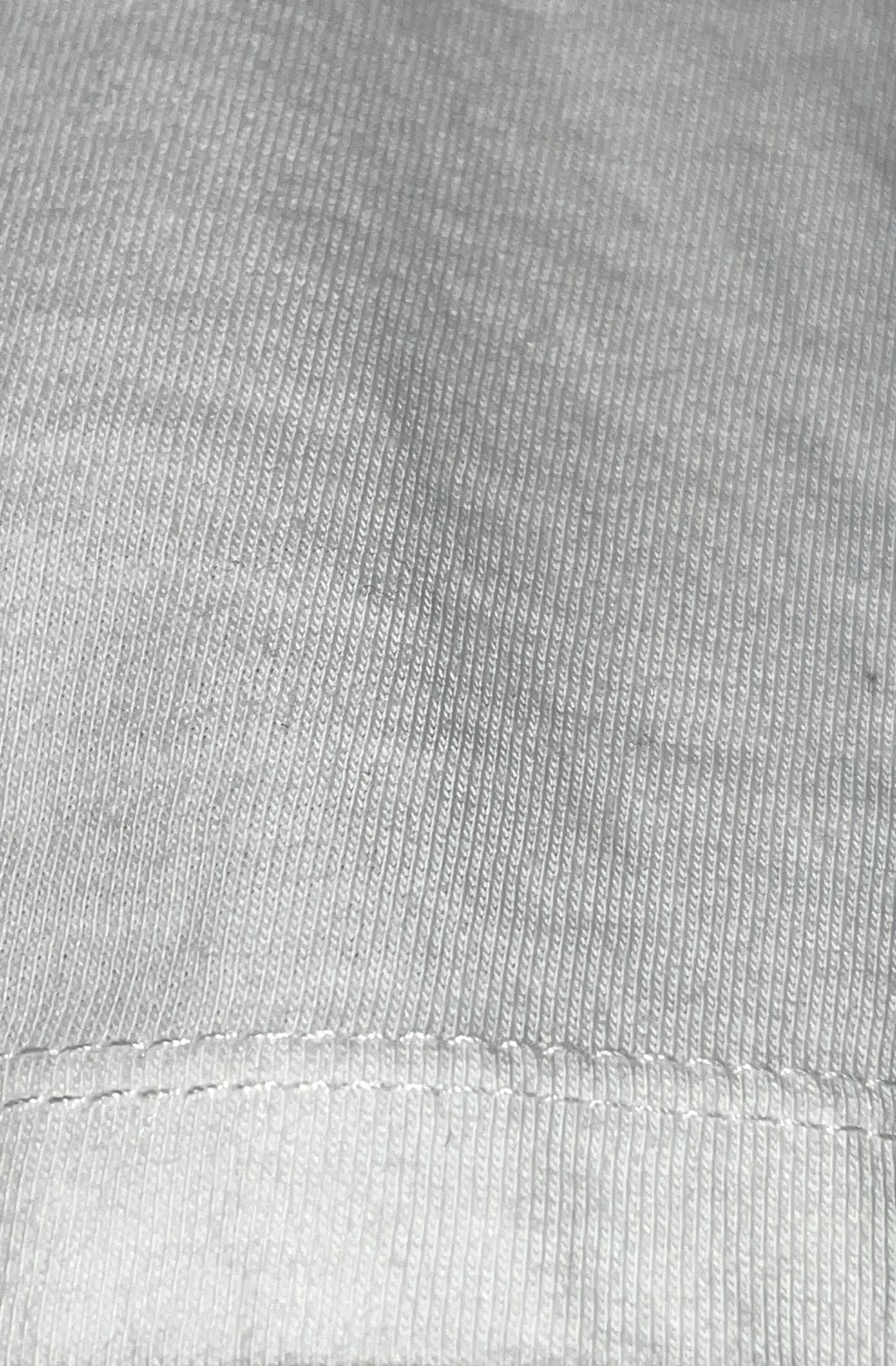 Close-up of white organic cotton fabric with a visible stitch sleeve edge detail