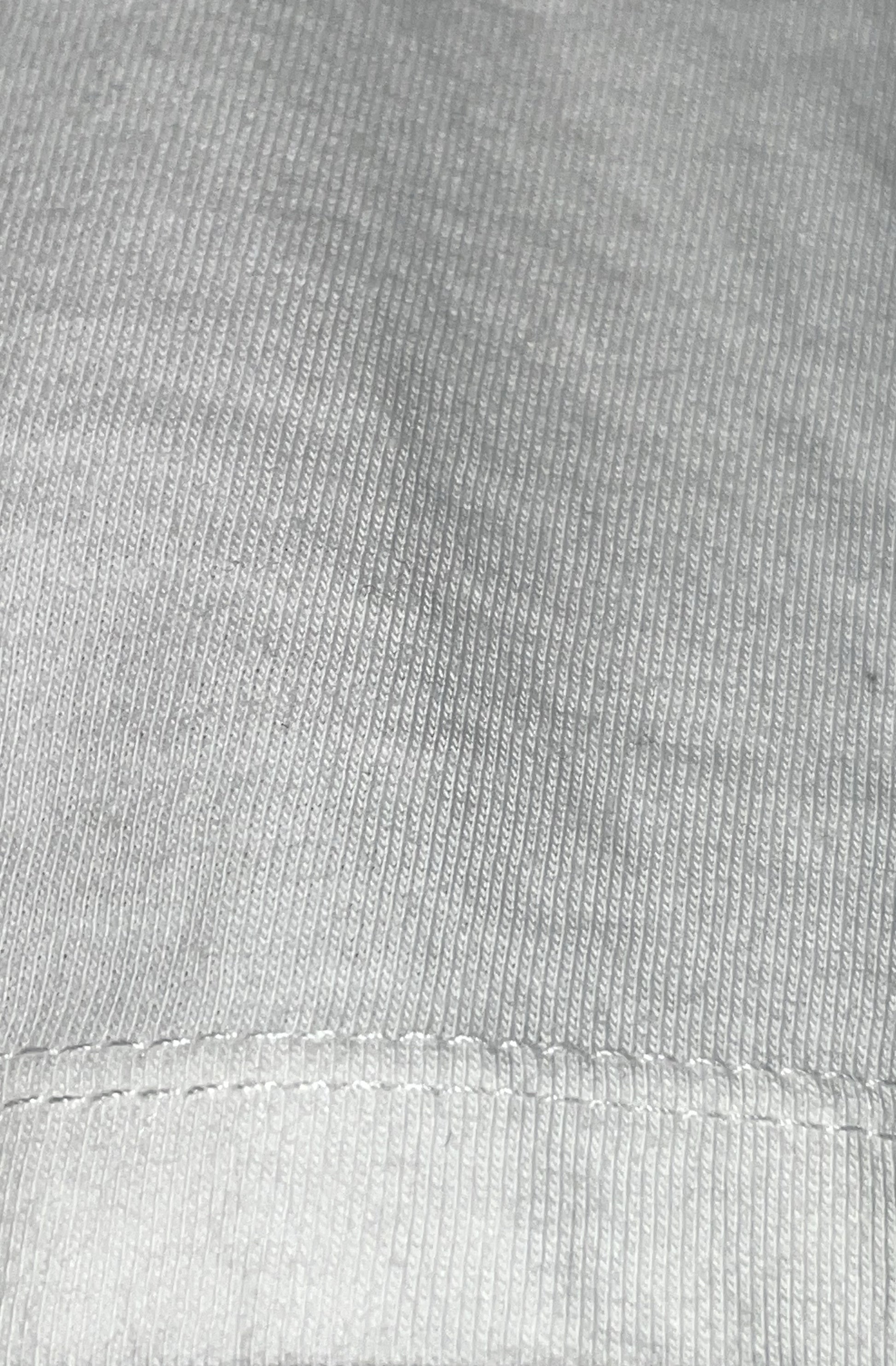 Close-up of white organic cotton fabric with a visible stitch sleeve edge detail