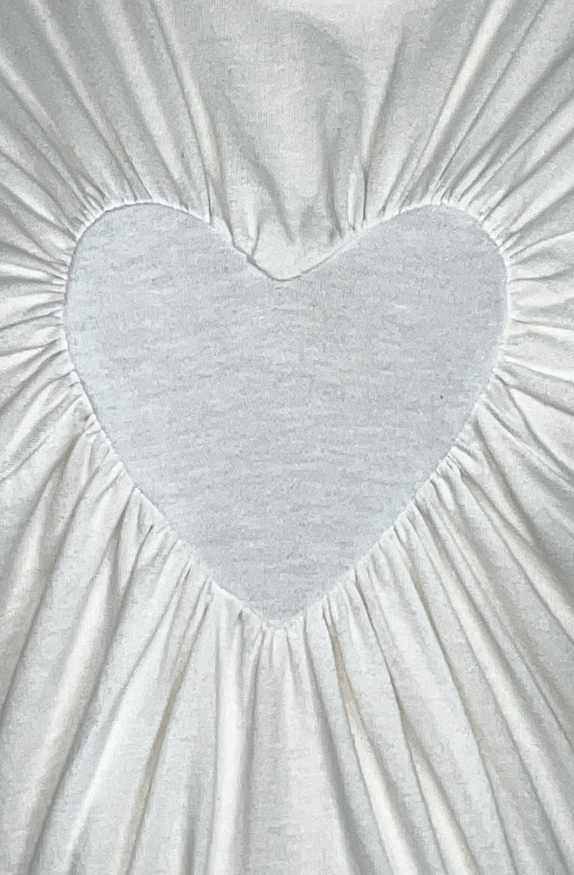 Gathered heart-shaped detail on a textured white organic cotton fabric t-shirt background