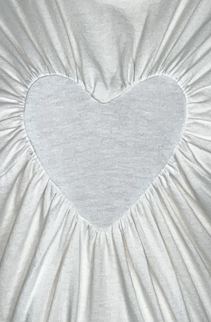 Gathered heart-shaped detail on a textured white organic cotton fabric t-shirt background