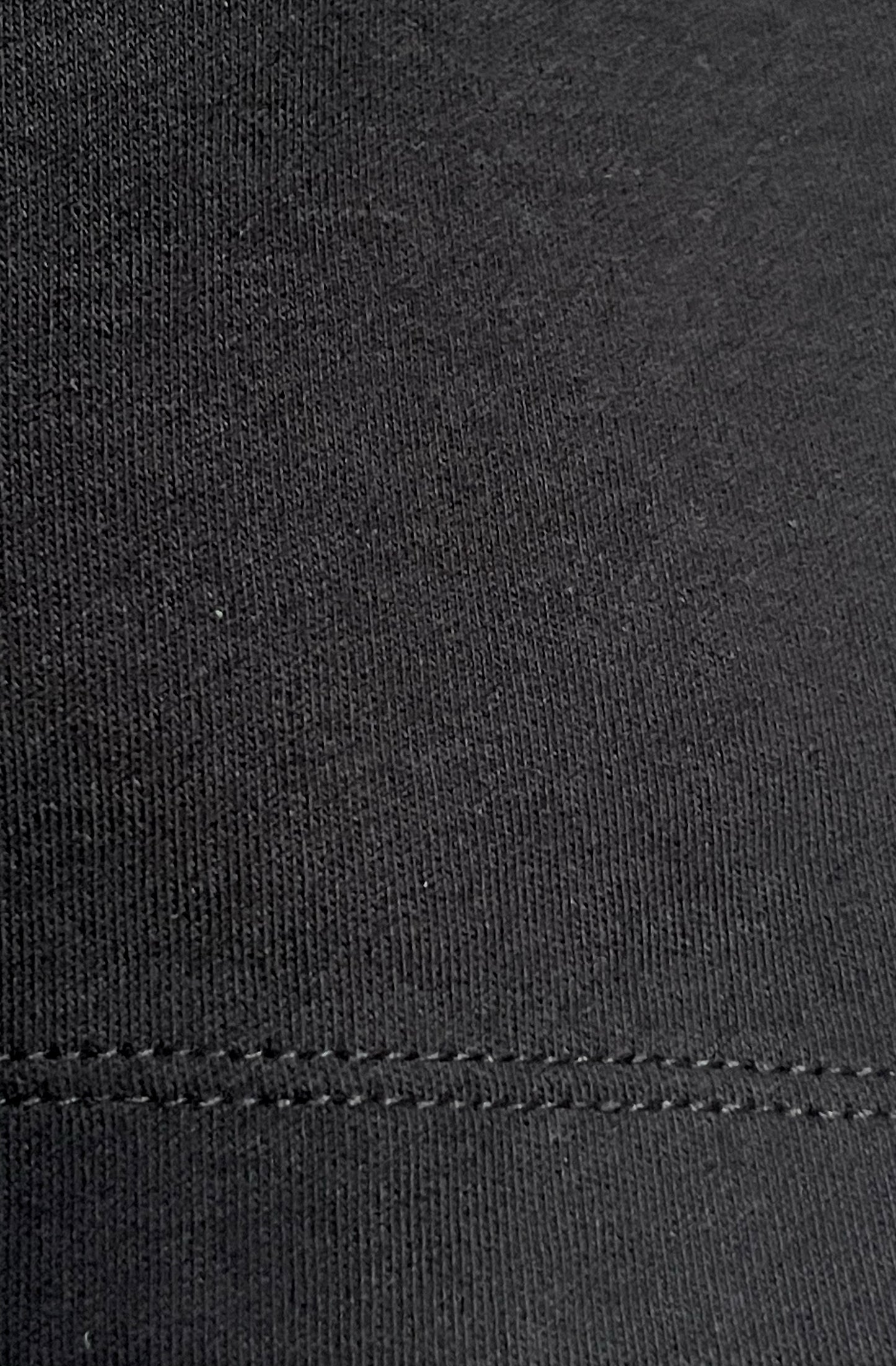 Close-up of black organic cotton texture with a visible stitch hem.