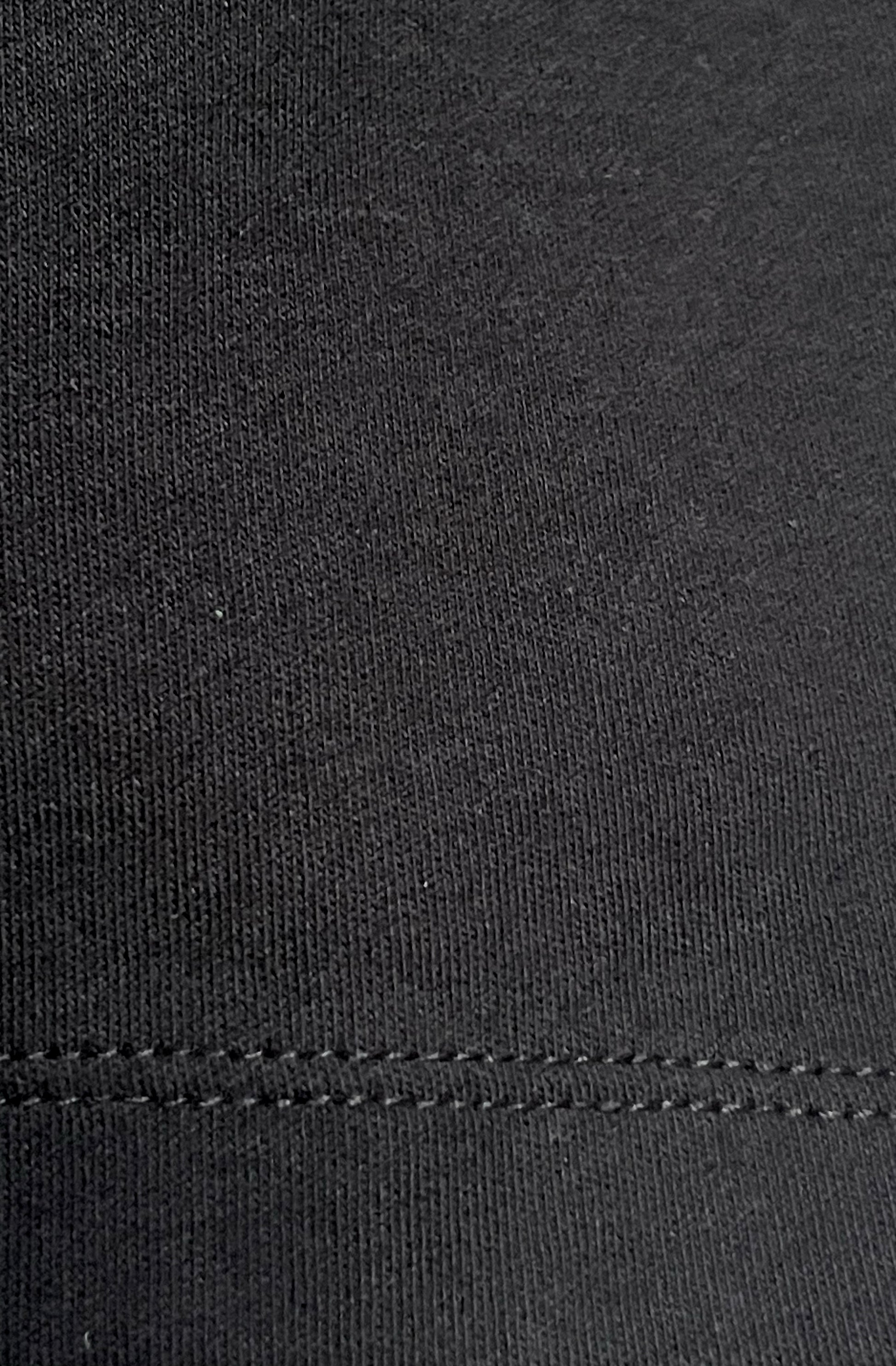 Close-up of black organic cotton texture with a visible stitch hem.