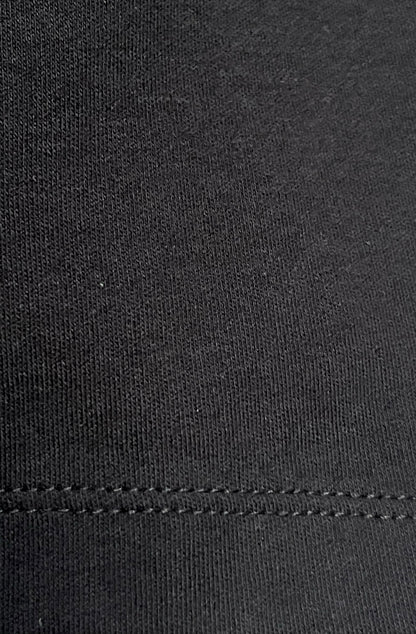 Close-up of black organic cotton texture with a visible stitch hem.
